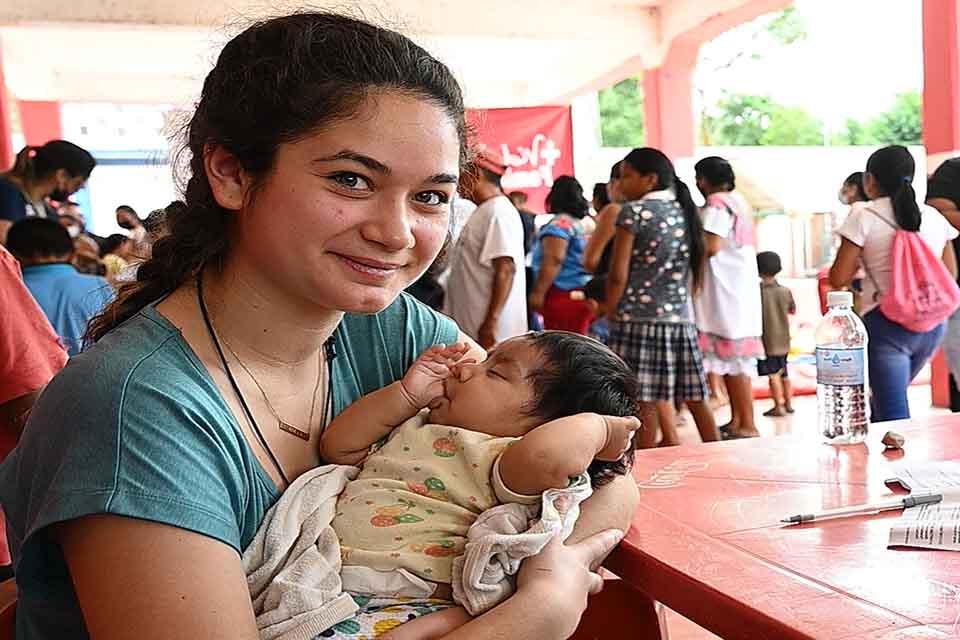 A student holds a young child while on a mission trip